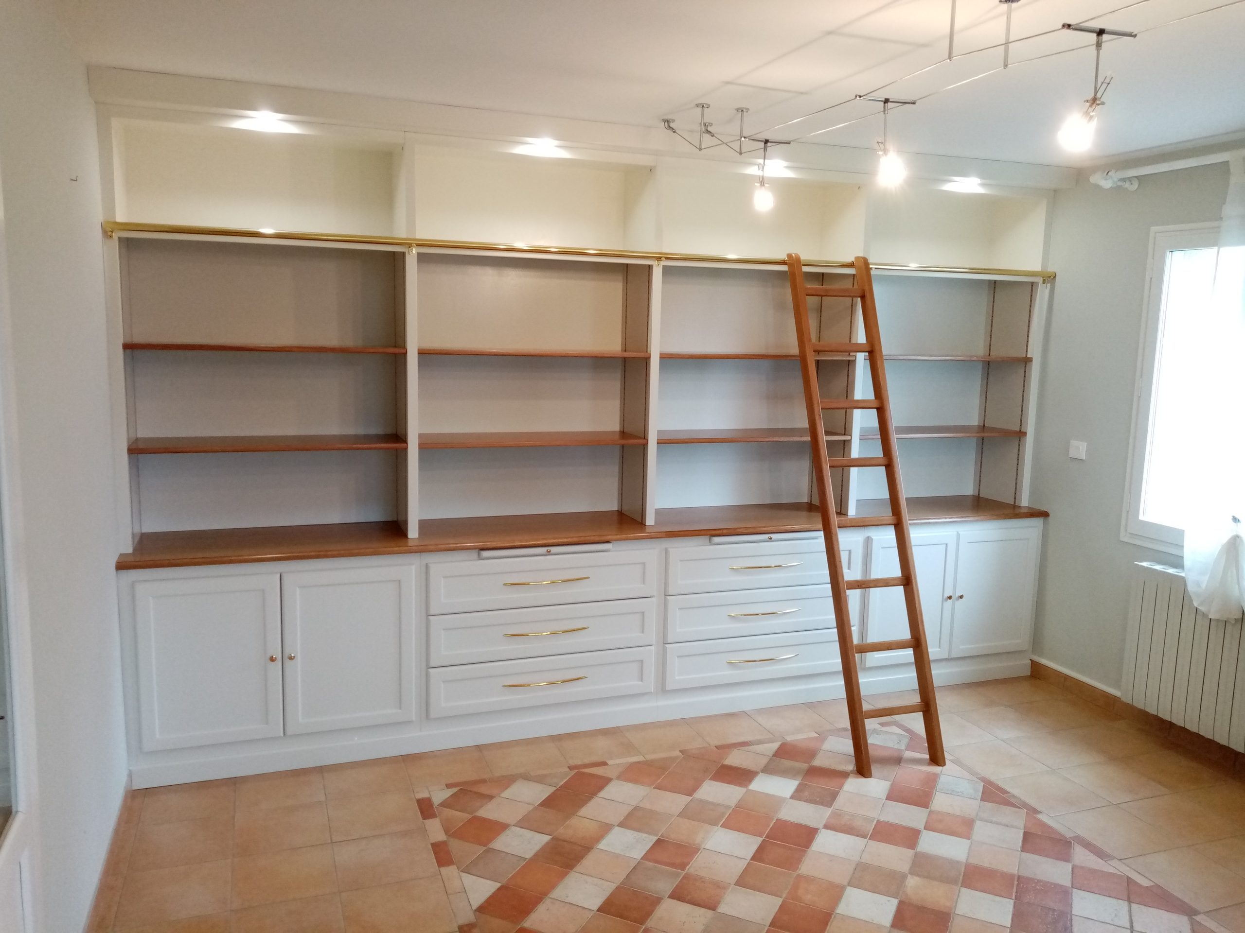 Bibliothèque en bois sur mesure adaptée aux dimensions de la pièce, avec étagères et rangements intégrés